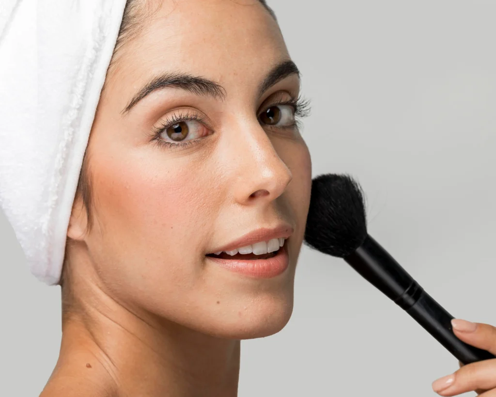 Chica aplicándose bronzer en el rostro