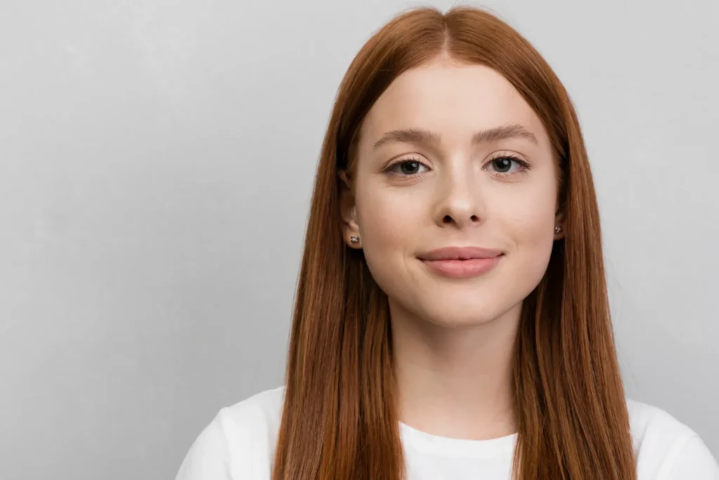 Mujer de cabello pelirrojo liso con mejillas suaves y facciones de rostro redondo