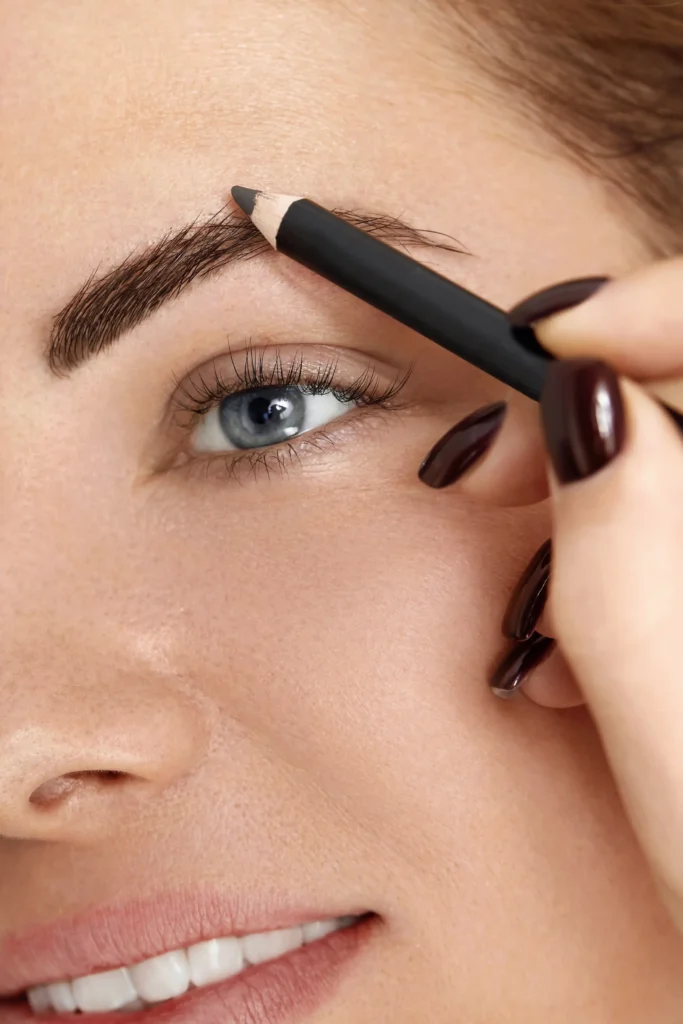 Mujer aplicando lápiz para cejas para definir y rellenar, creando cejas perfectas y naturales.