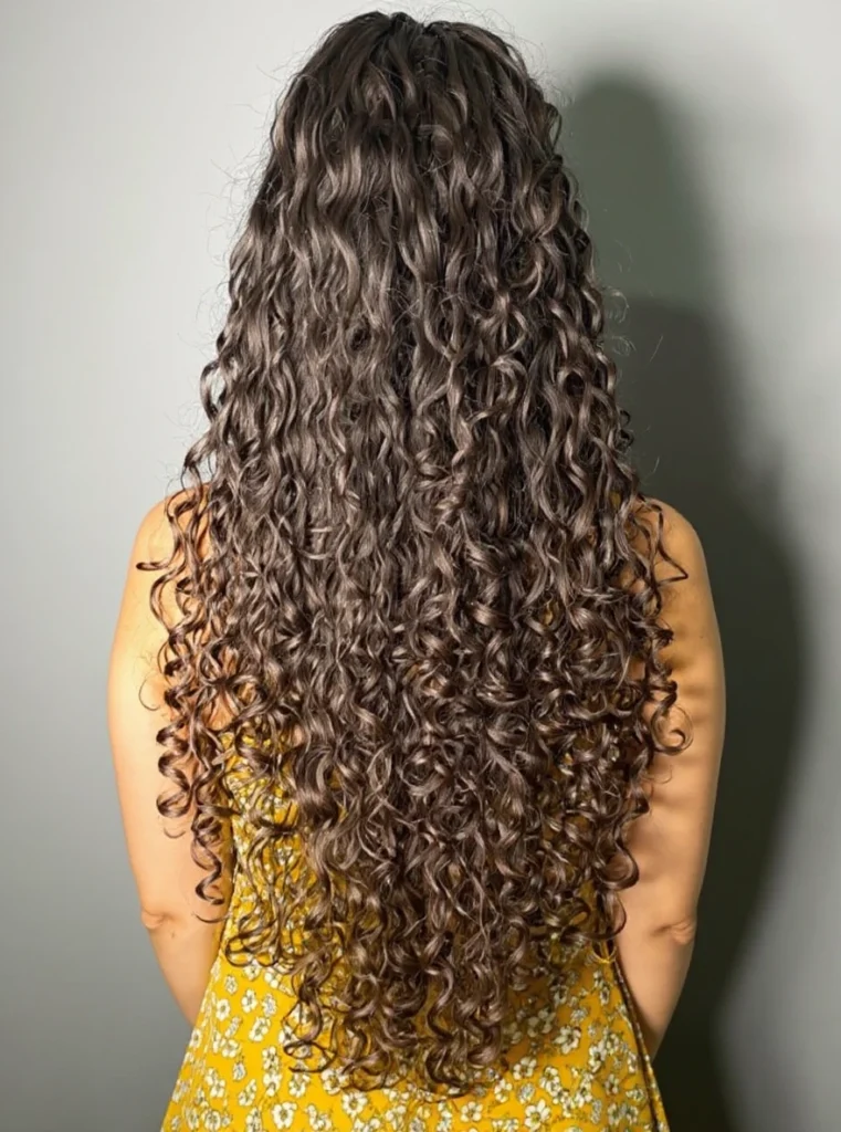 Cabello rizado teñido de castaño con brillo y definición.