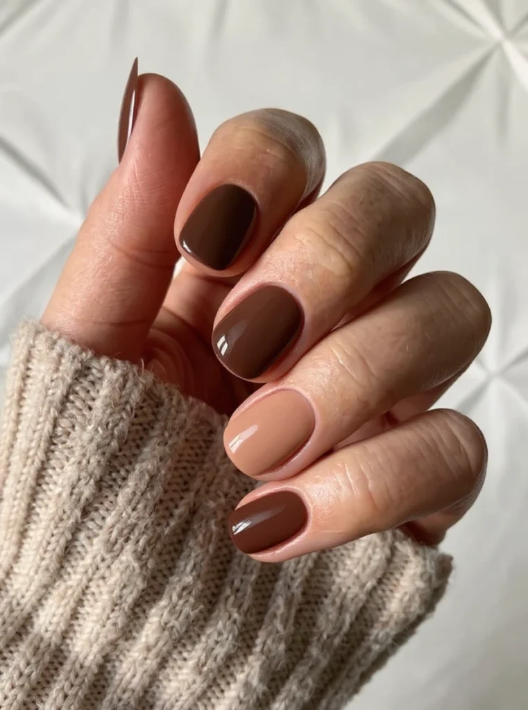 Uñas almendradas en marrón neutro con jersey de punto en look otoñal.