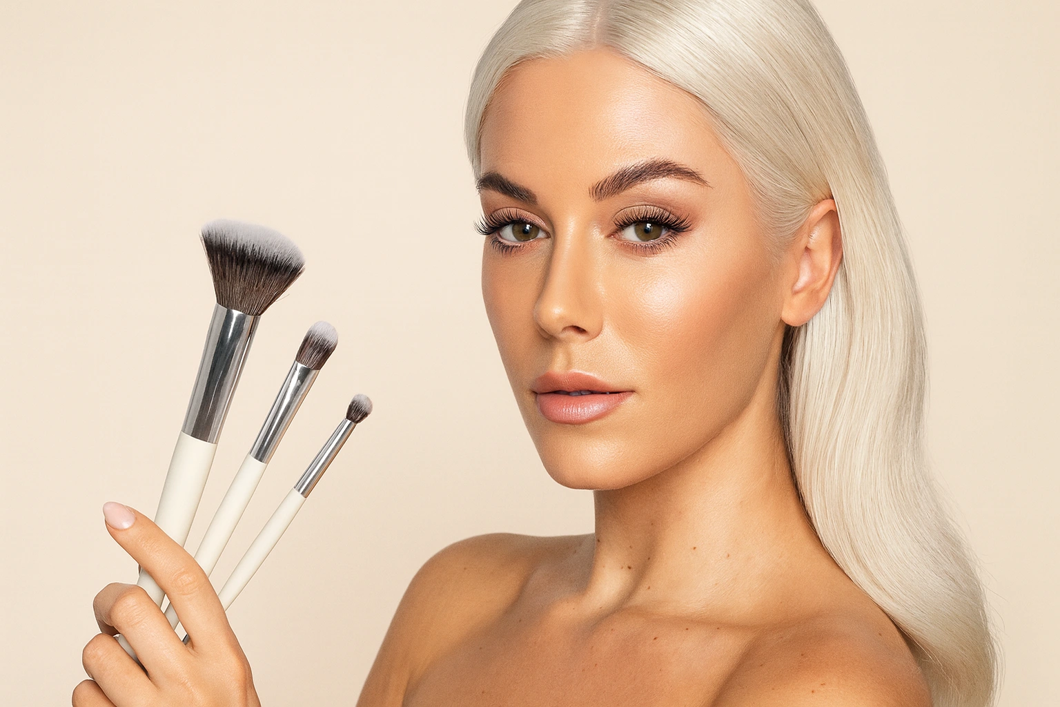 Chica rubia con maquillaje completo sostiene brochas