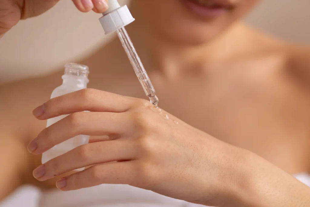 Mujer aplicando un sérum facial como parte del paso de tratamientos específicos en su rutina.