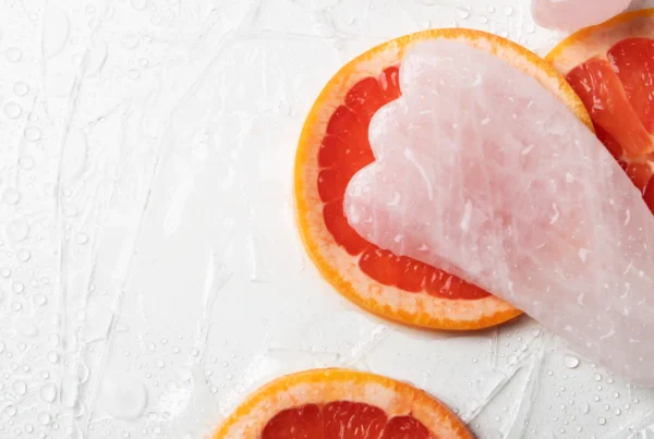 Piedra guasha acompañada de toronja, reflejando un masaje facial natural para iluminar y tonificar la piel.