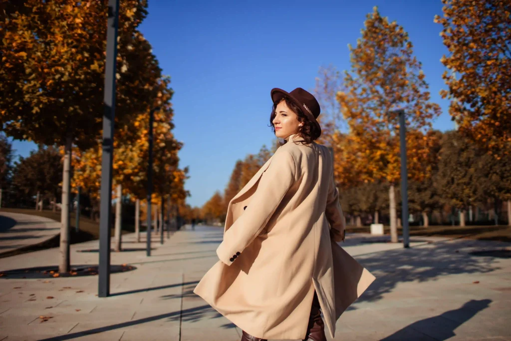 Mujer elegante con abrigo oversize y bufanda, reflejando la tendencia de capas y texturas para mantener calor.