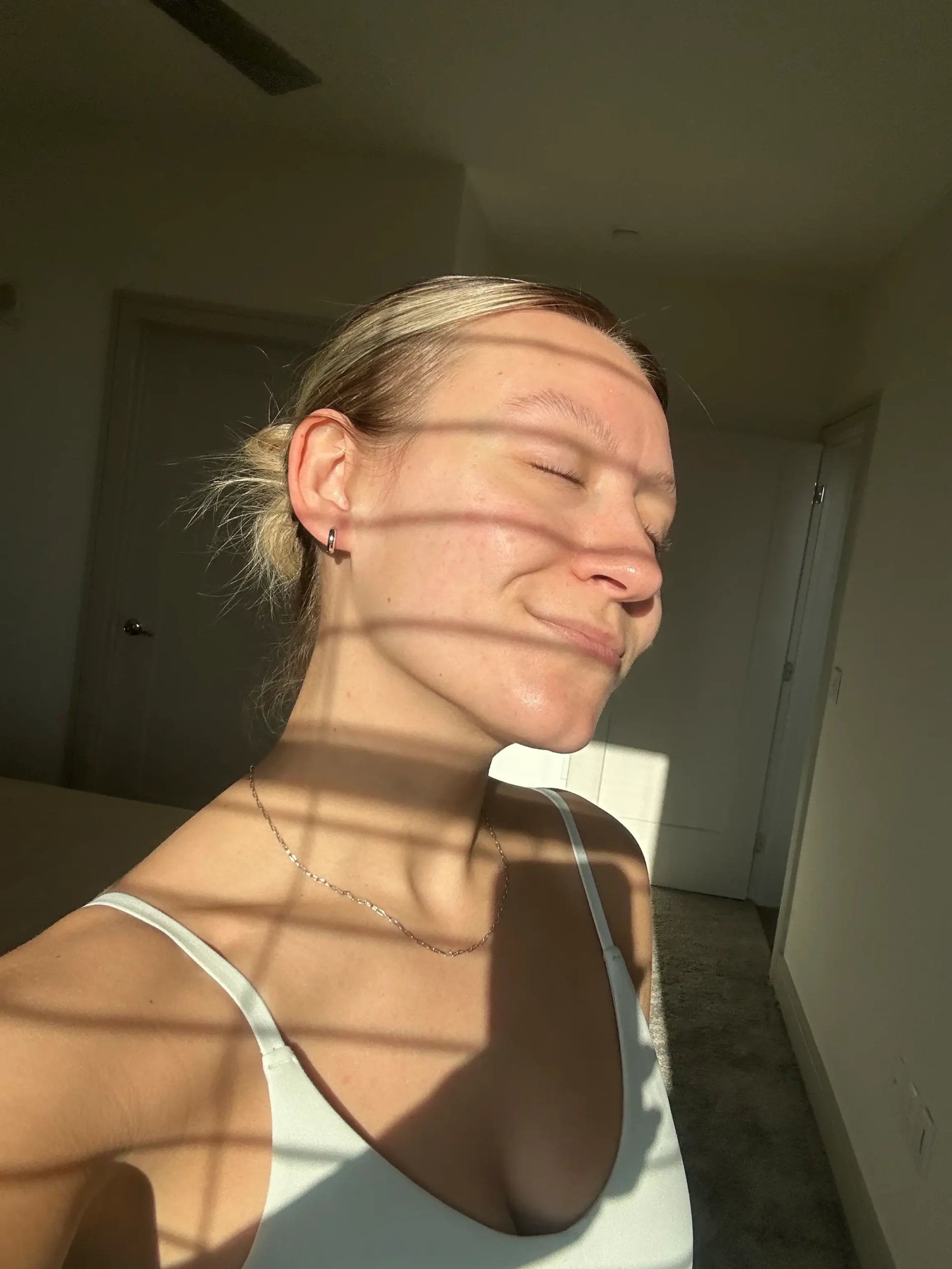 Mujer con los ojos cerrados y el rostro iluminado disfrutando de un momento de bienestar y relajación