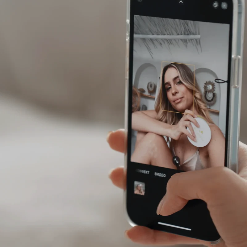 Persona sosteniendo un teléfono mientras toma una selfie con un filtro de belleza aplicado.