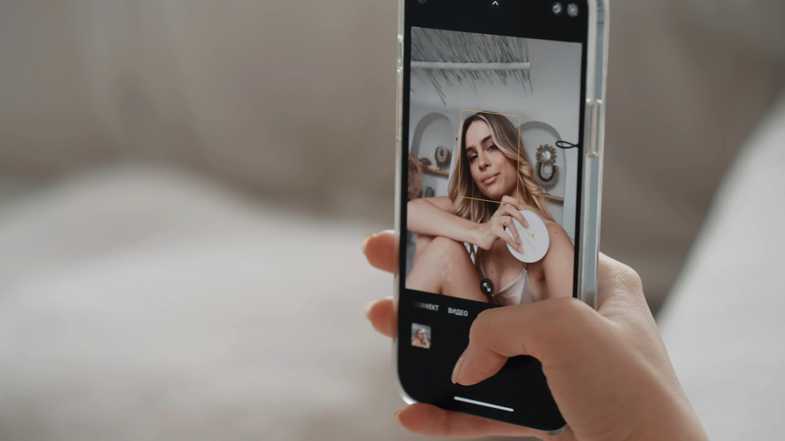 Persona sosteniendo un teléfono mientras toma una selfie con un filtro de belleza aplicado.