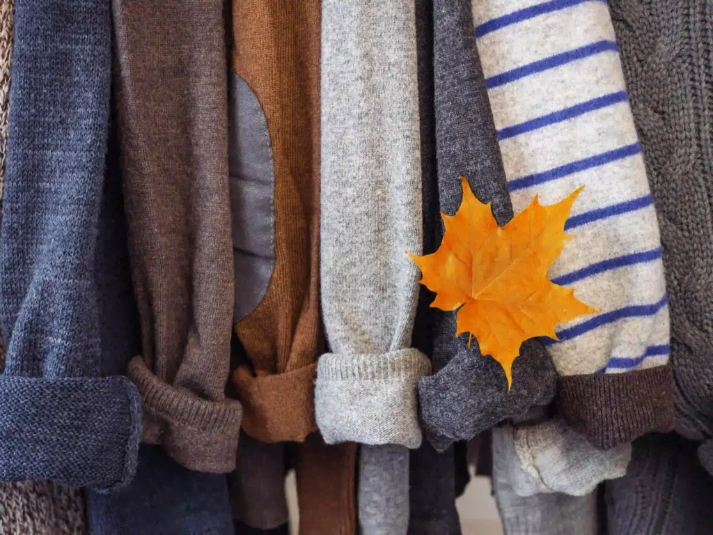 Ropa de invierno colgada en perchas, mostrando gabardinas, suéteres y abrigos versátiles para diferentes ocasiones.