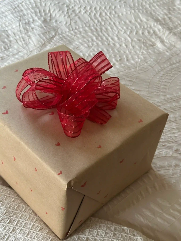 Regalo envuelto en papel kraft con cinta roja, sugerencia DIY para presentación emotiva.