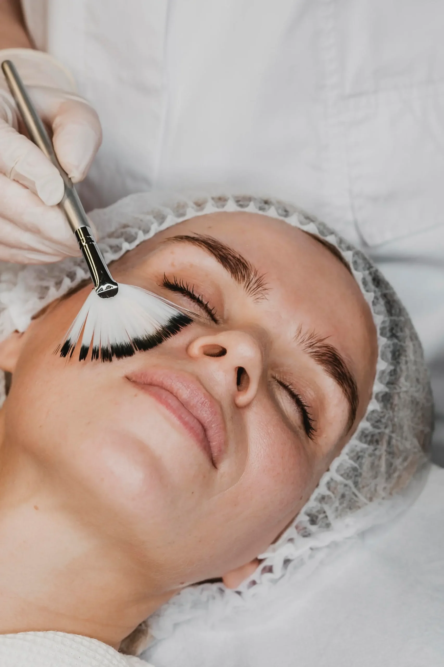 Mujer joven aplicándose tratamiento facial con profesional