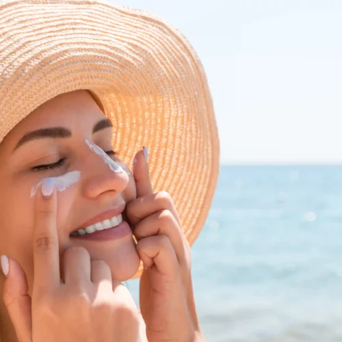 Mujer aplicando protector solar facial antes de exponerse al sol en la playa