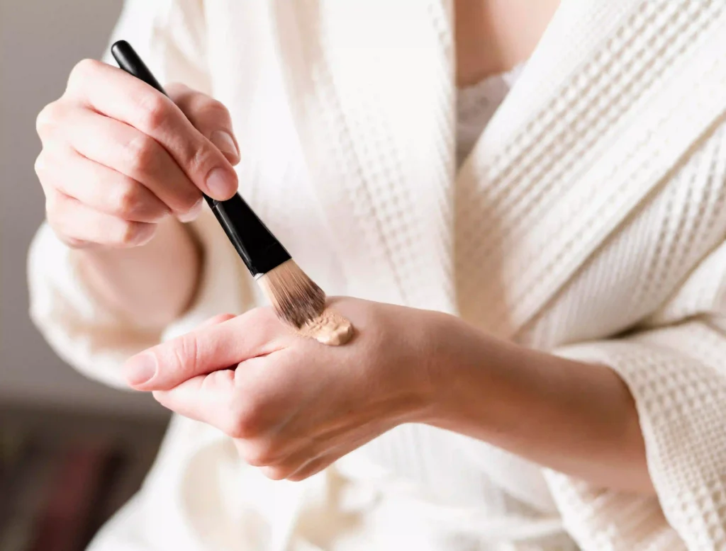 aplicación de base líquida con brocha para maquillaje básico