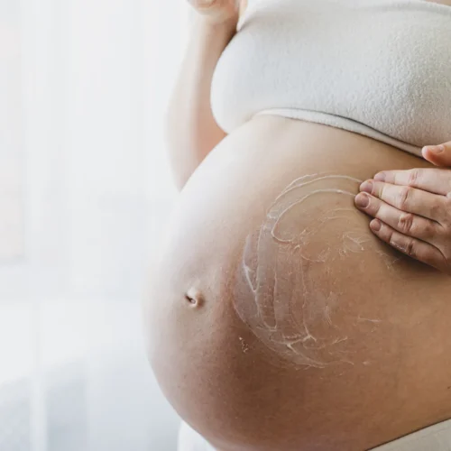 Embarazada aplicando crema en el abdomen con movimientos suaves y ascendentes.