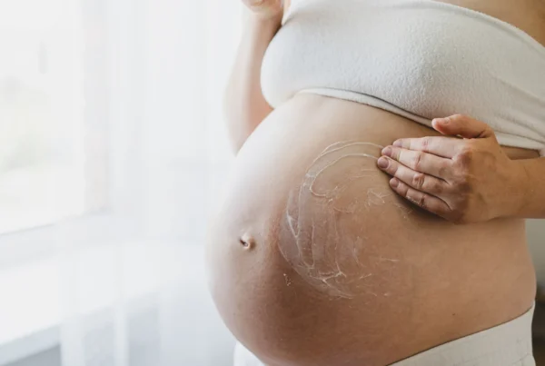 Embarazada aplicando crema en el abdomen con movimientos suaves y ascendentes.
