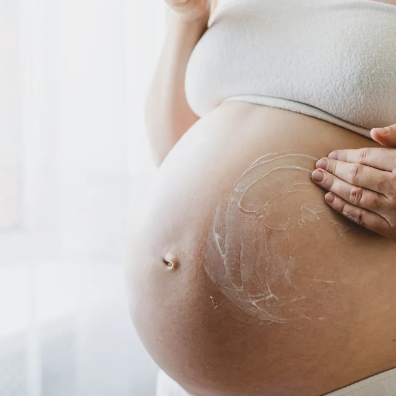 Embarazada aplicando crema en el abdomen con movimientos suaves y ascendentes.