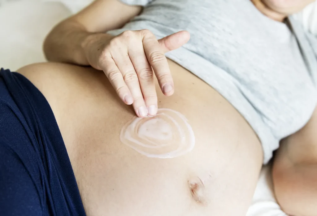 Aplicación de crema corporal en el baby bump para mejorar la hidratación de la piel.