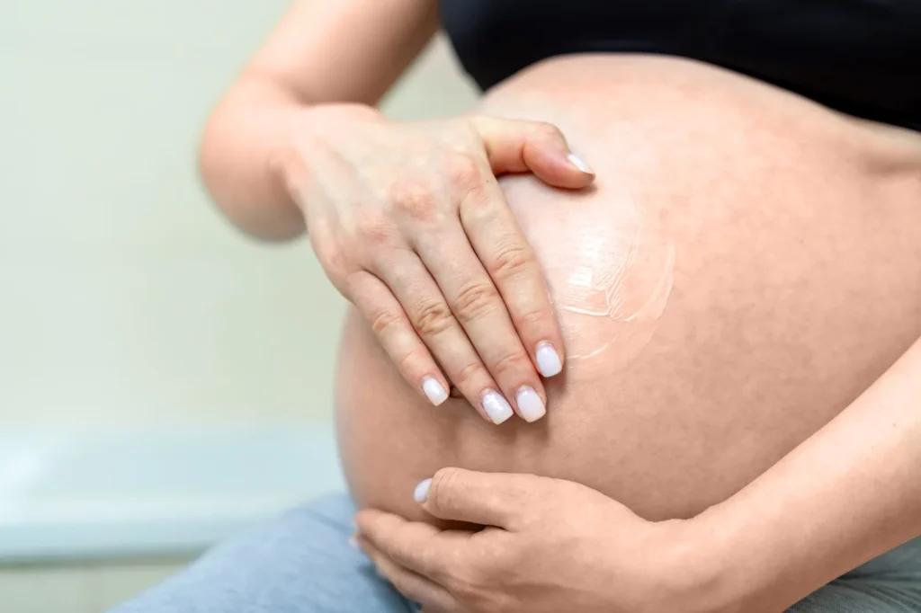 Masaje con crema en el vientre para cuidar la piel y reducir la tirantez durante el embarazo.