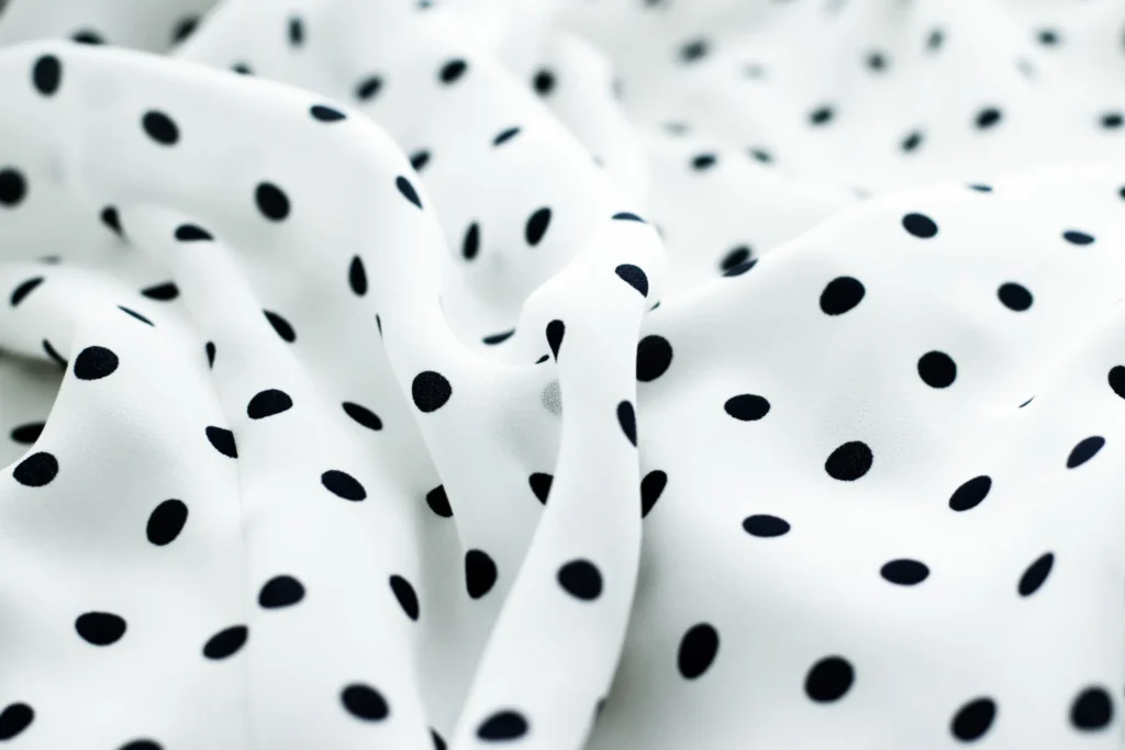 Textura de tela blanca con lunares negros, estampado polka dots sobre tejido fluido