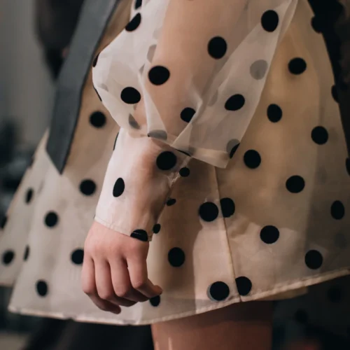 Detalle de vestido de tul transparente con lunares negros y manga abullonada