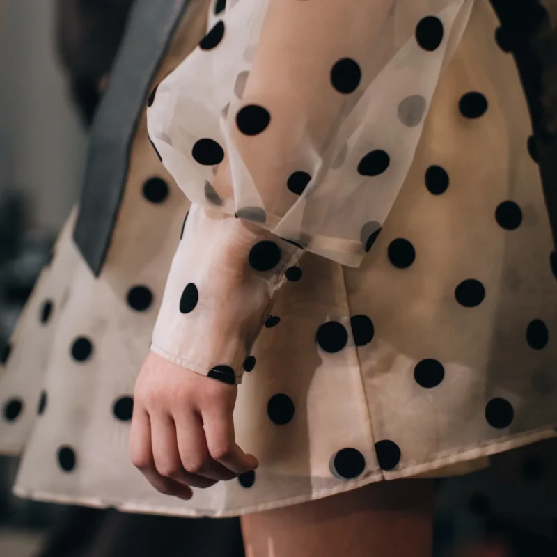 Detalle de vestido de tul transparente con lunares negros y manga abullonada
