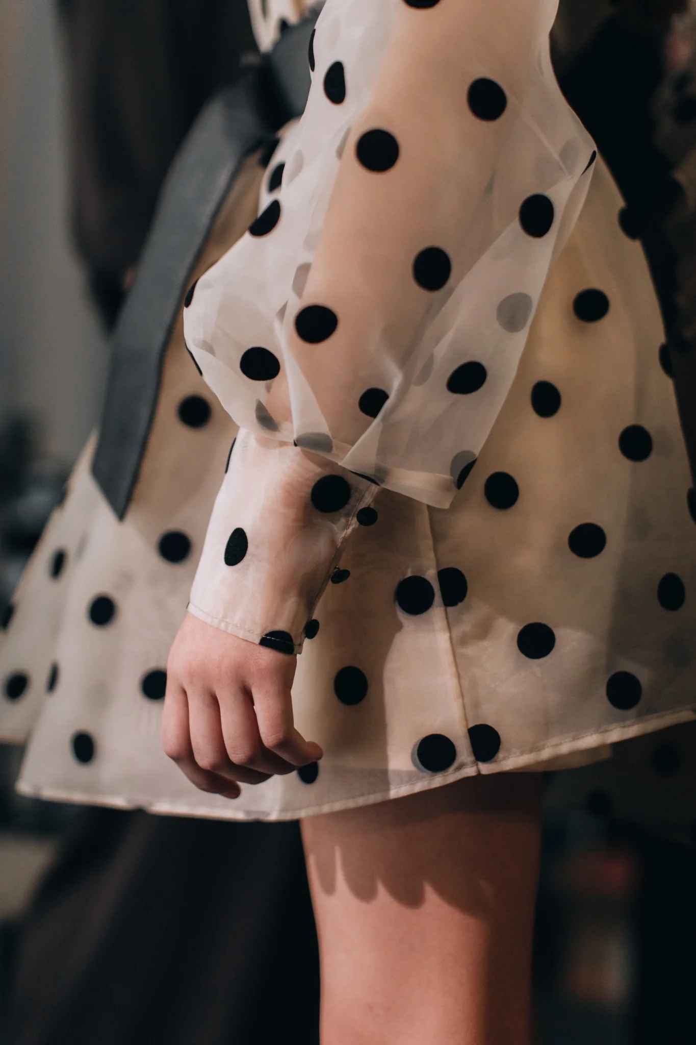 Detalle de vestido de tul transparente con lunares negros y manga abullonada