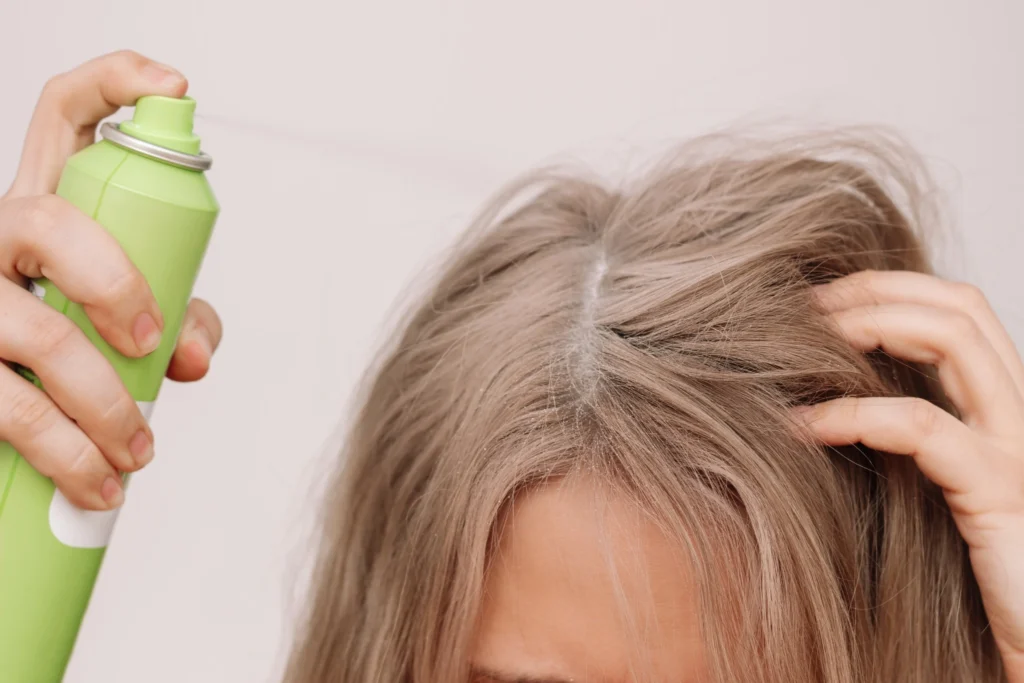 Mujer aplicando champú en seco directamente en las raíces del cabello