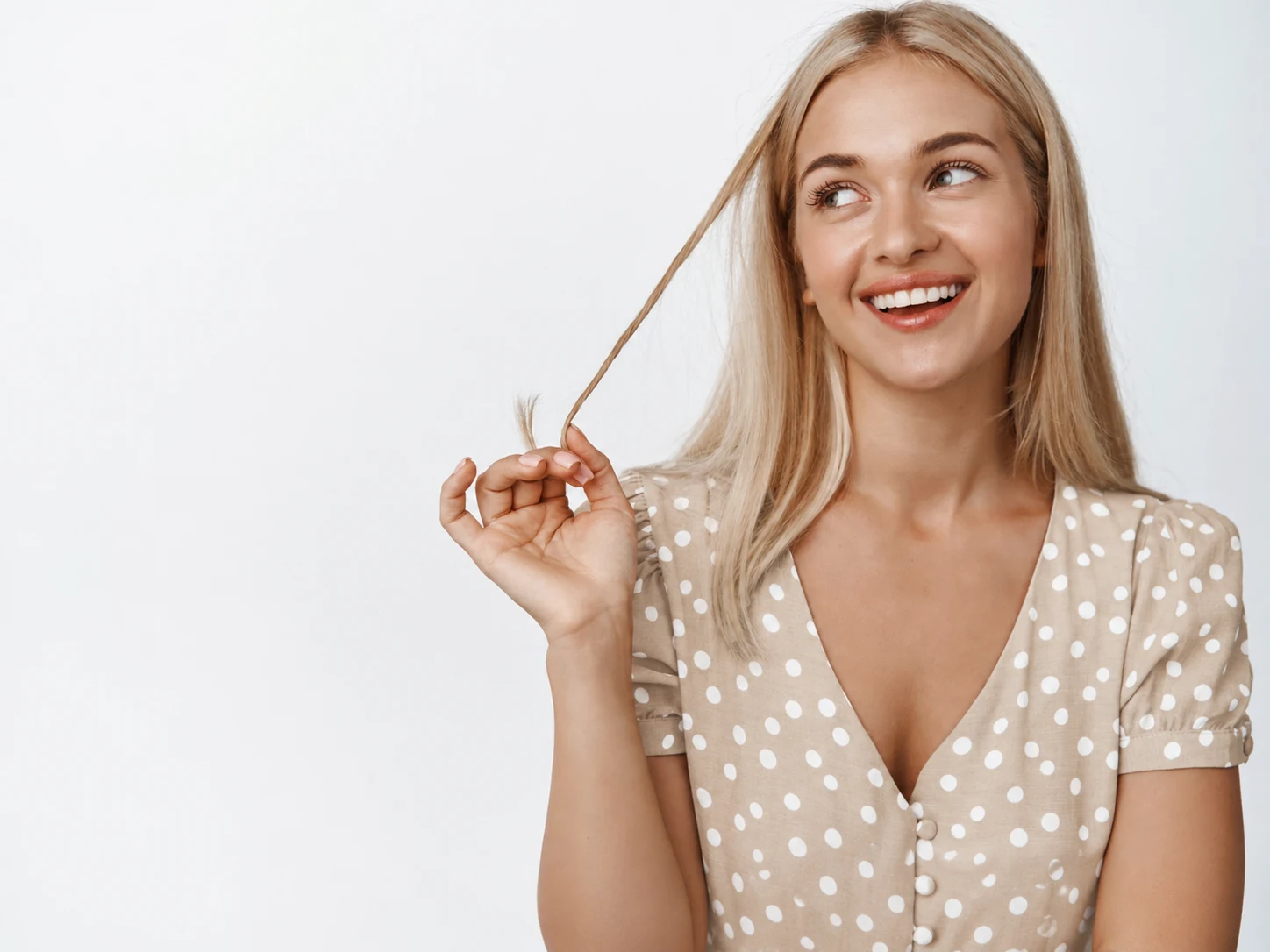 Mujer rubia sonriendo y sujetando un mechón de pelo para ilustrar el crecimiento pelo
