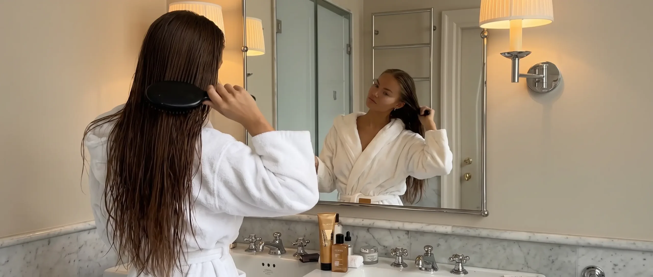Mujer cepillando su melena húmeda frente al espejo del baño después de lavarse el pelo graso