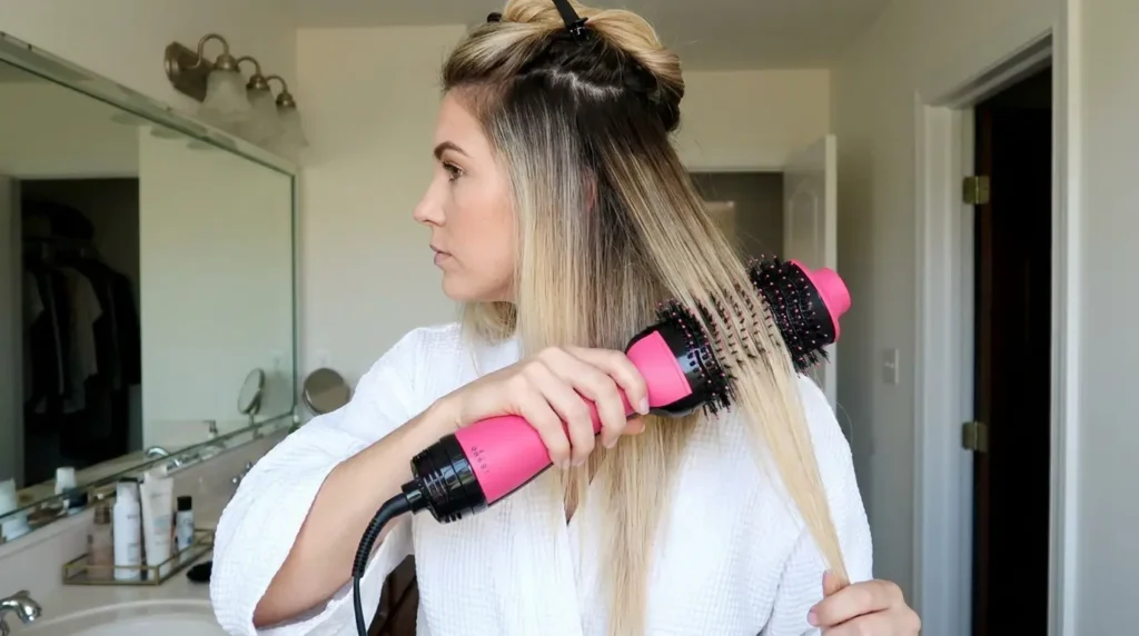 Mujer secando su melena con un cepillo de aire caliente, aplicando el calor en medios y puntas
