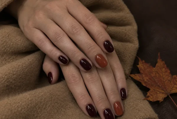 Manicura de otoño 2026 en burdeos con uña de acento terracota sobre abrigo camel